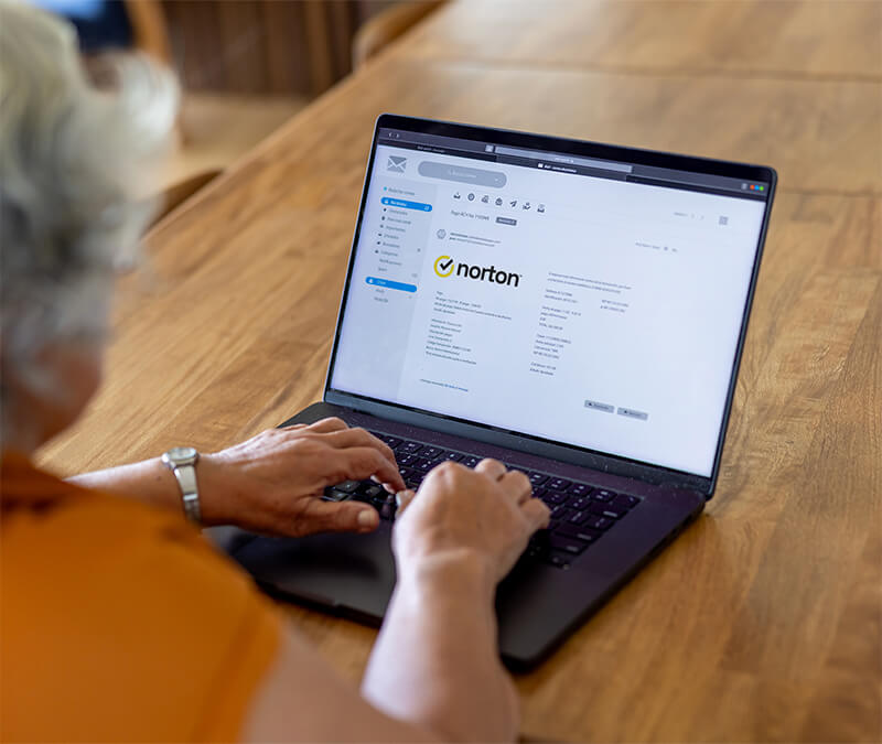Une femme consulte ses e-mails sur son ordinateur portable et se demande si elle a reçu un e-mail d'escroquerie prétendument envoyé par Norton.