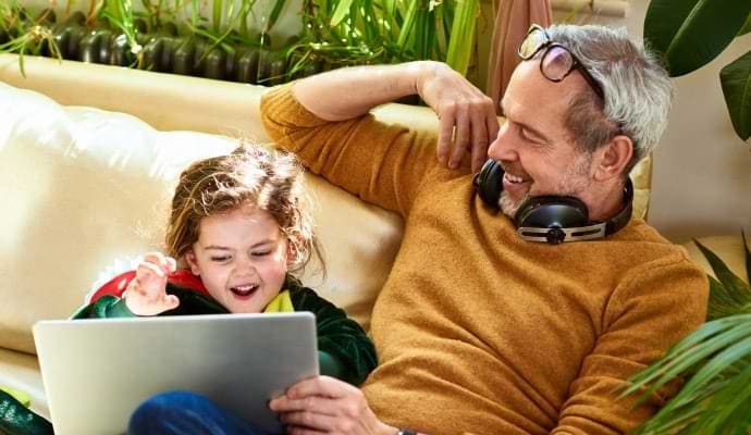 Homme portant un casque audio, montrant quelque chose sur un ordinateur portable à une petite fille